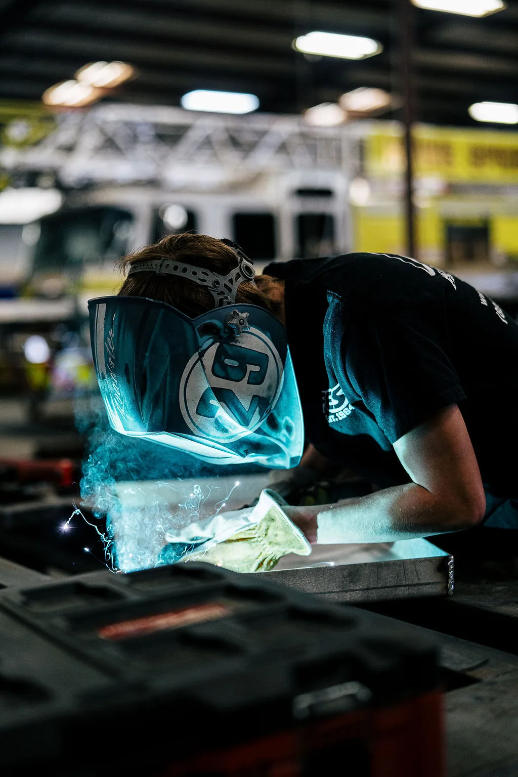 FES welder joining aluminum with an aerial fire apparatus behind him in the Sumter shop
