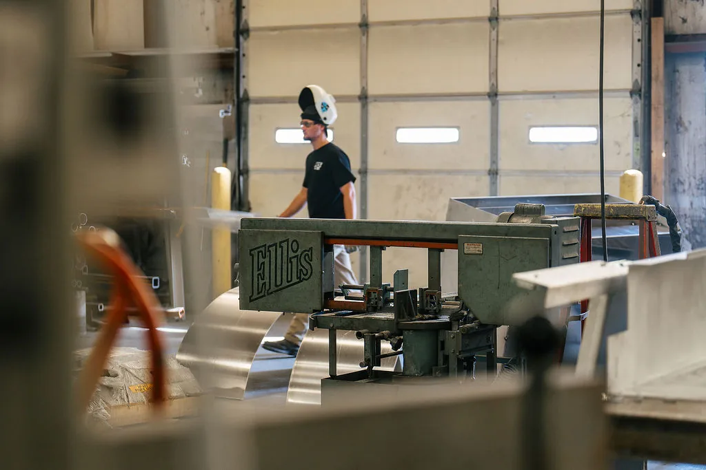 FES fabricator feeding aluminum sheet through a horizontal band saw