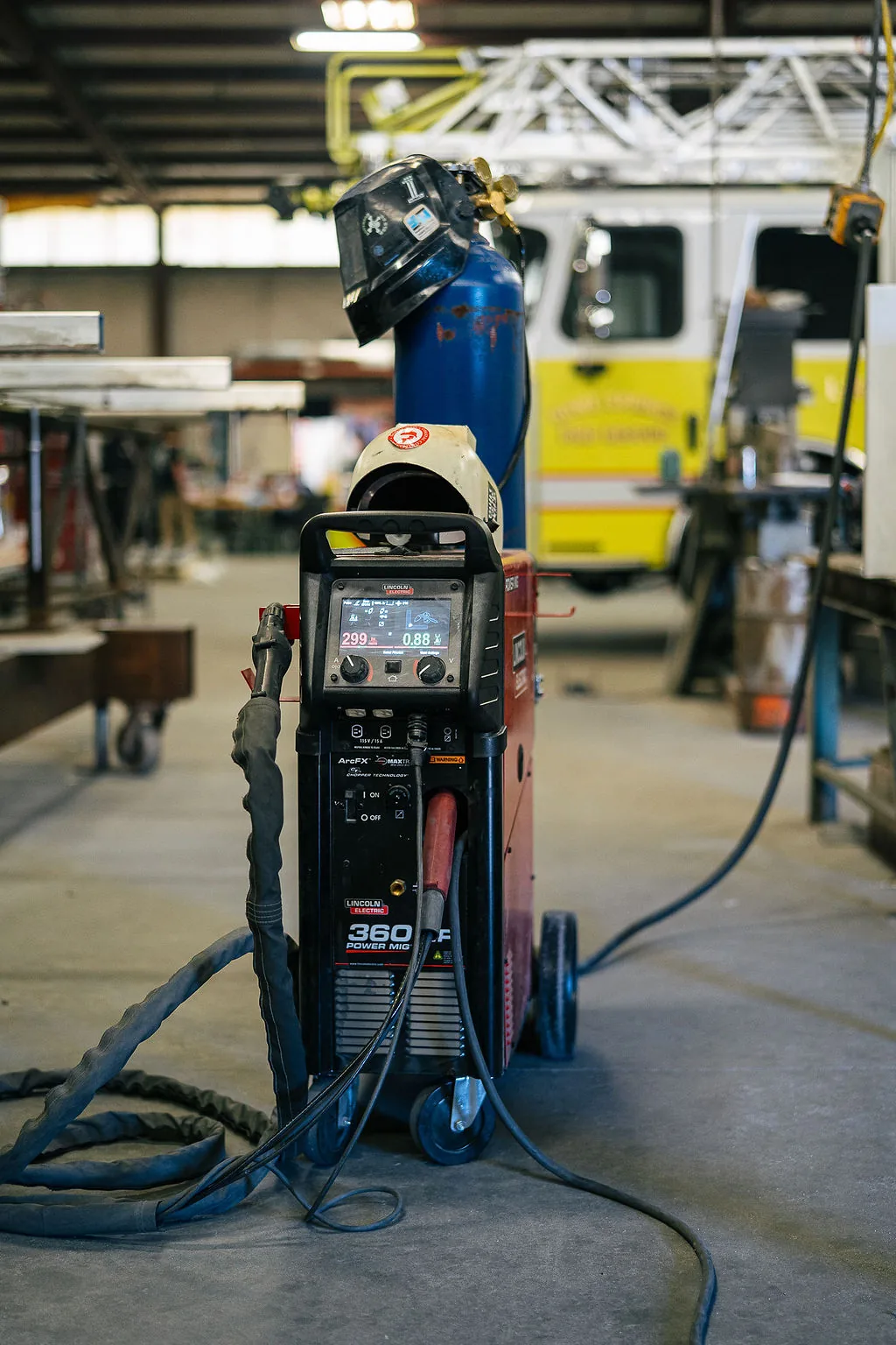 Welding power source and helmet staged in front of an aerial ladder fire apparatus in the FES shop