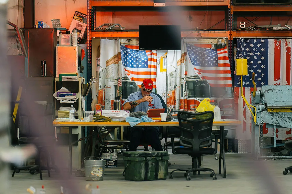 FES team member working at a desk on the shop floor in front of American flag curtains